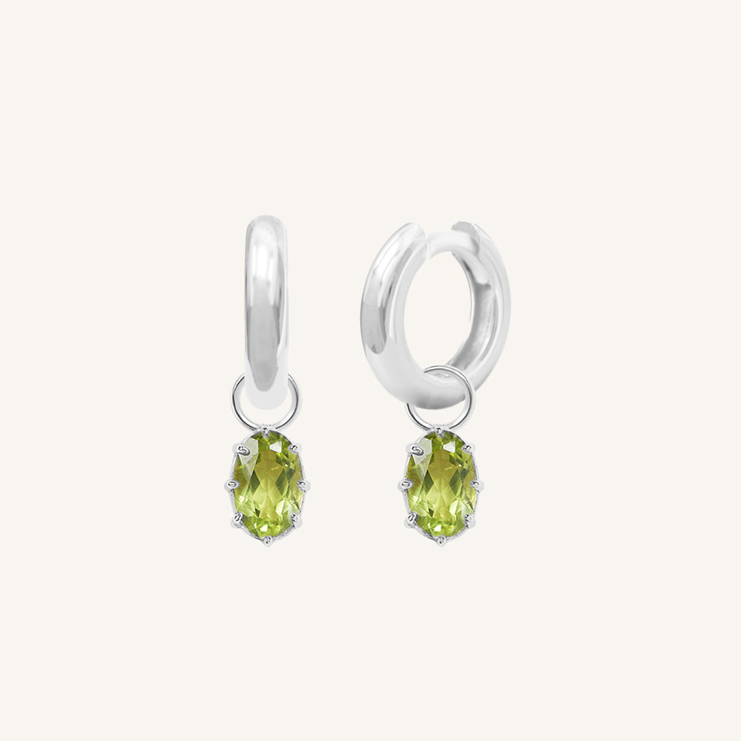 A pair of silver-tone hoop earrings with olive green charms attached to them.