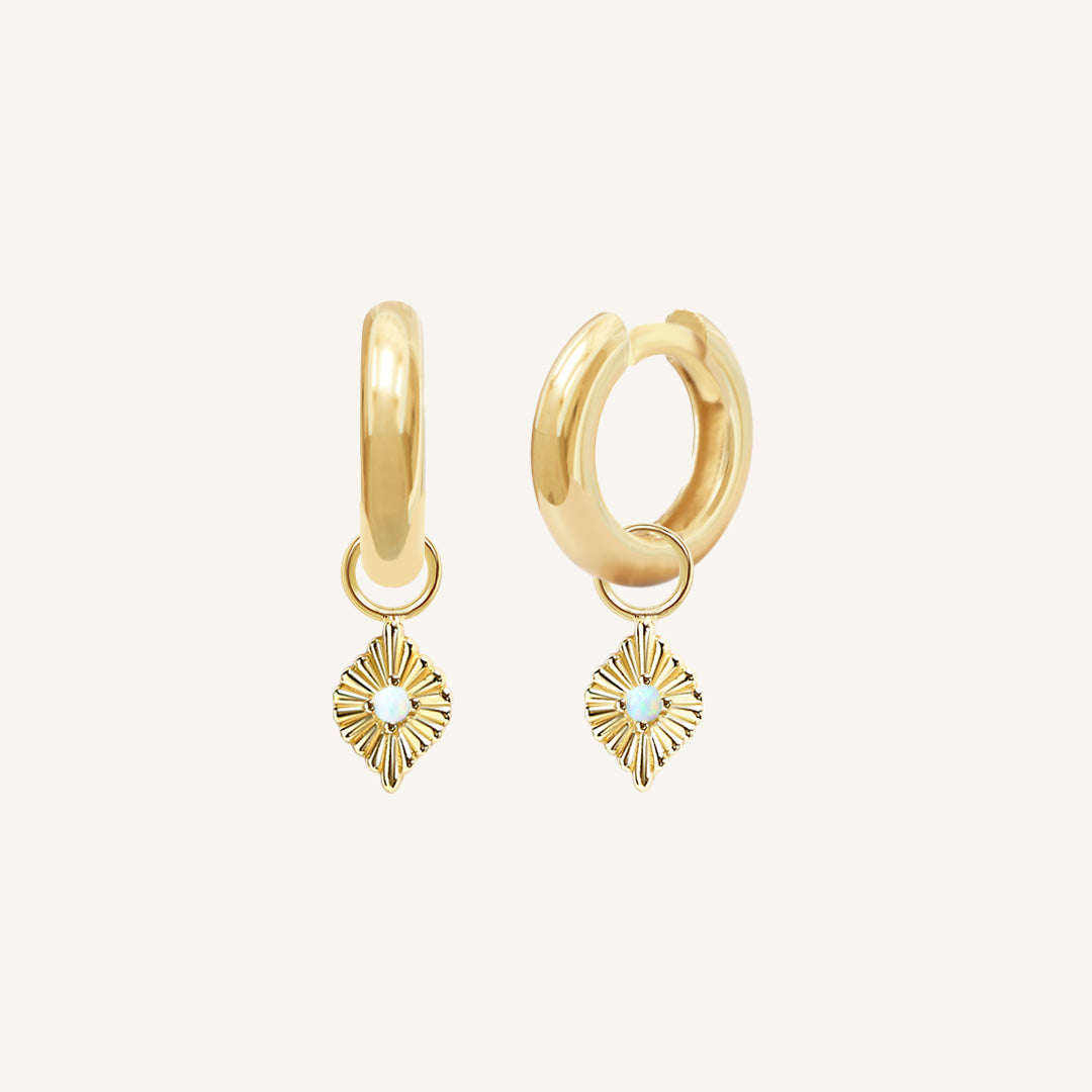 A pair of gold hoops with diamond shaped hoop charms featuring a faux opal