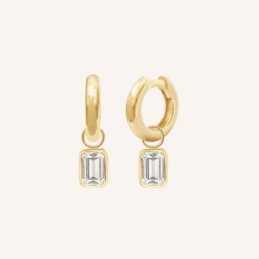 A pair of gold hoop earrings with radiant cut charms attached to the hoops.