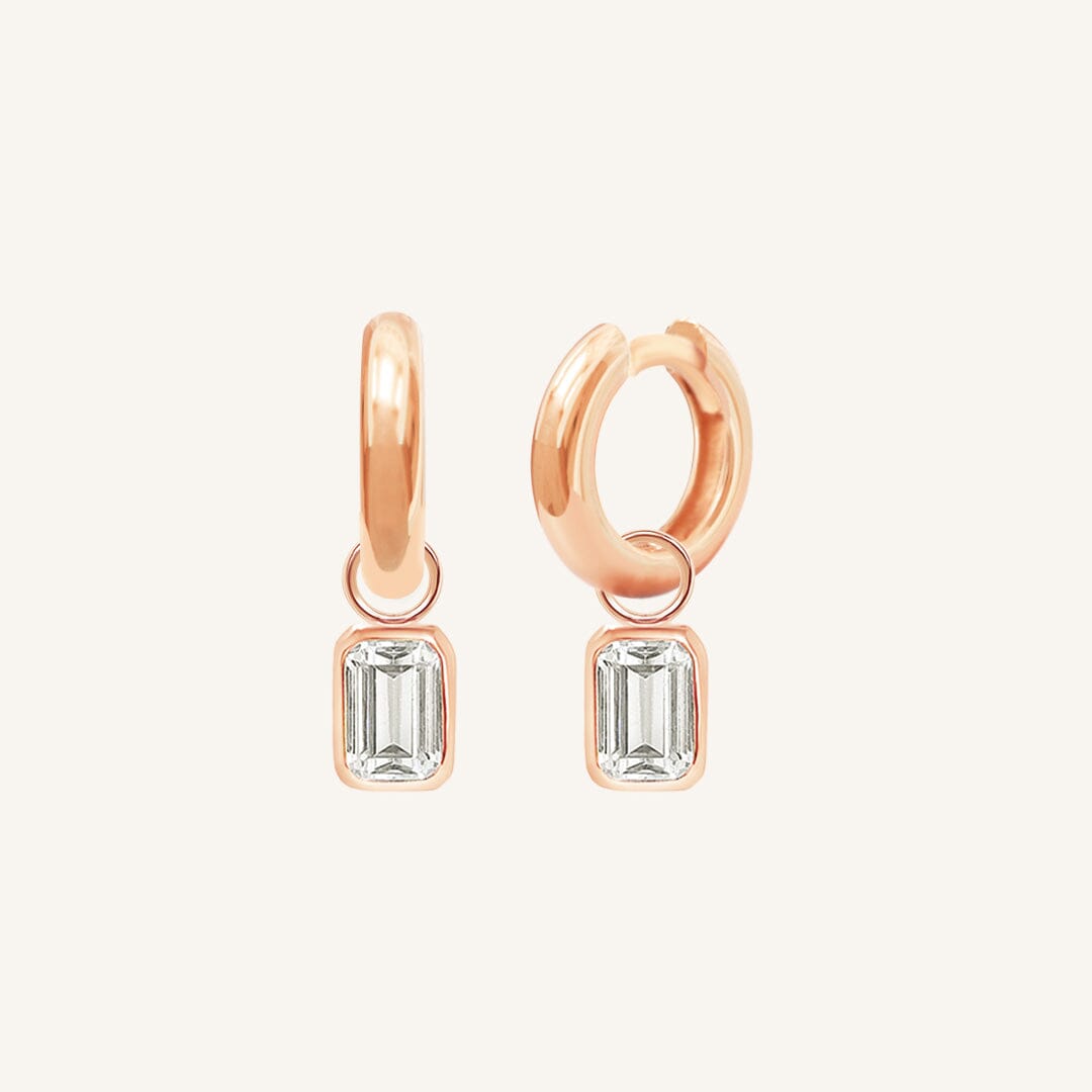A pair of gold-colored hoop earrings with transparent crystal embellishments.