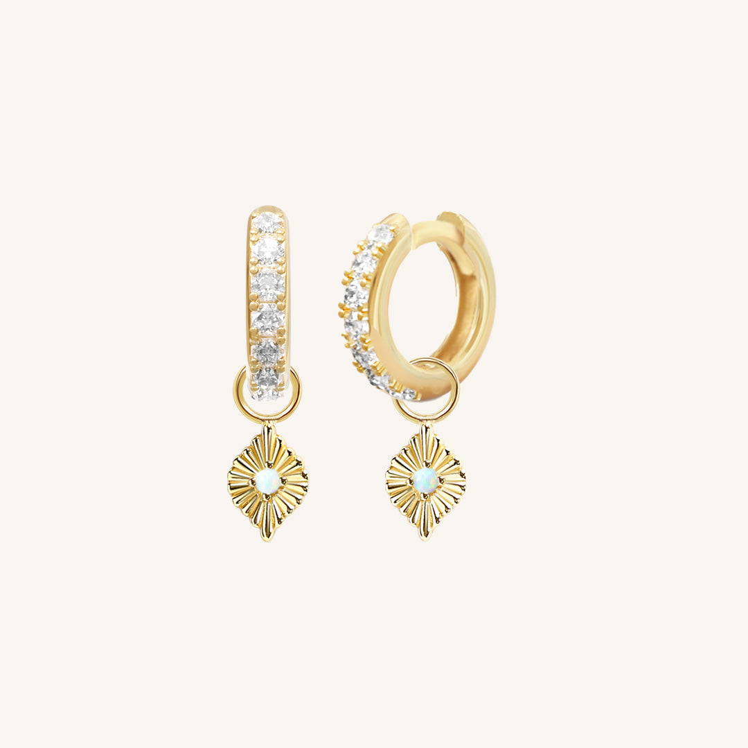 A pair of gold hoop earrings with cubic zirconia and diamond shaped hoop charms featuring a faux opal