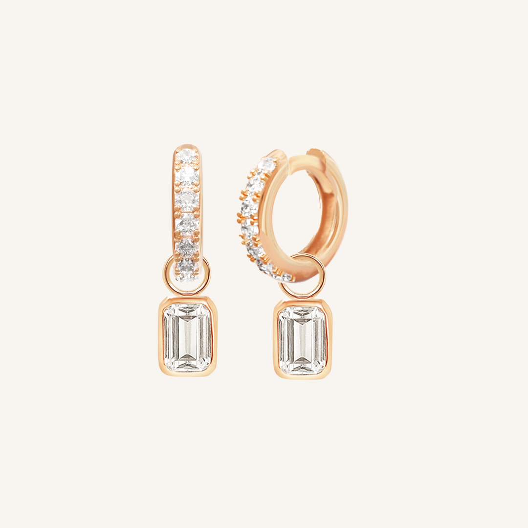 A pair of rose-tone radiant crystal hoop earrings with charm drops.