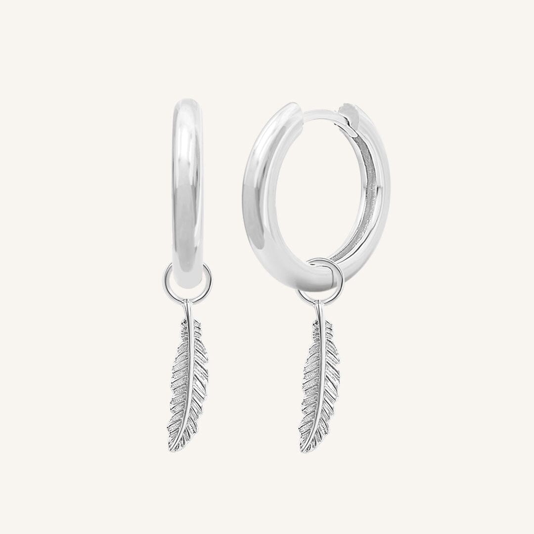 A pair of gold-colored hoop earrings with delicate feathers attached to the hoops.