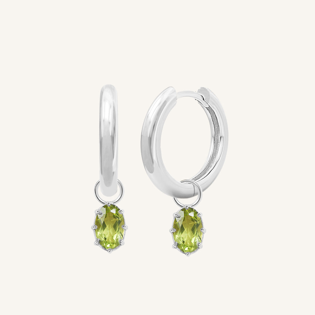 A pair of silver-tone hoop earrings with olive green charms attached to them.