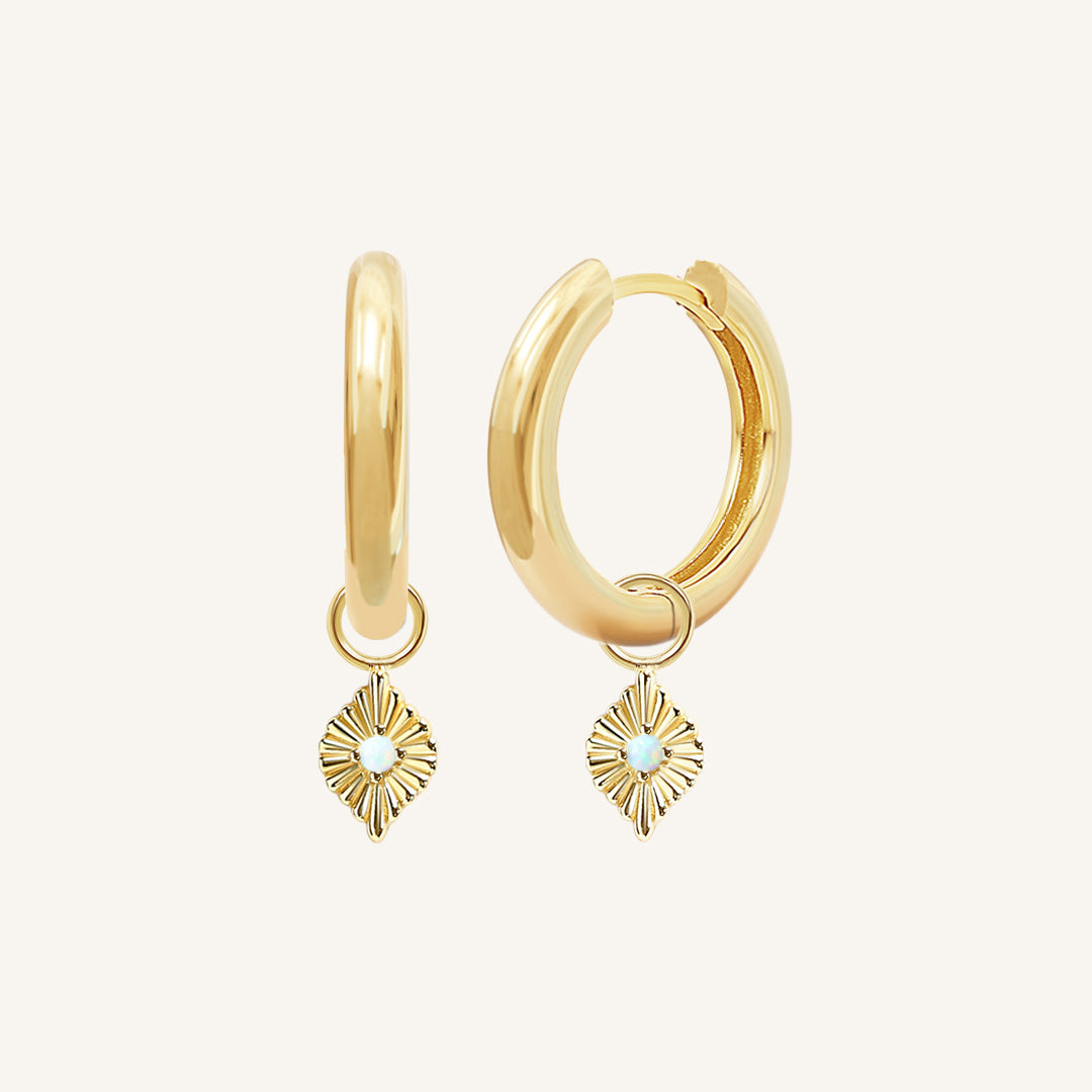 A pair of gold hoops with diamond shaped hoop charms featuring a faux opal