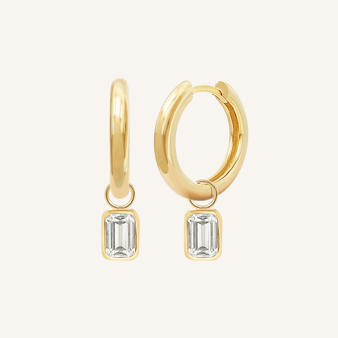A pair of gold-colored hoop earrings with transparent crystal embellishments.