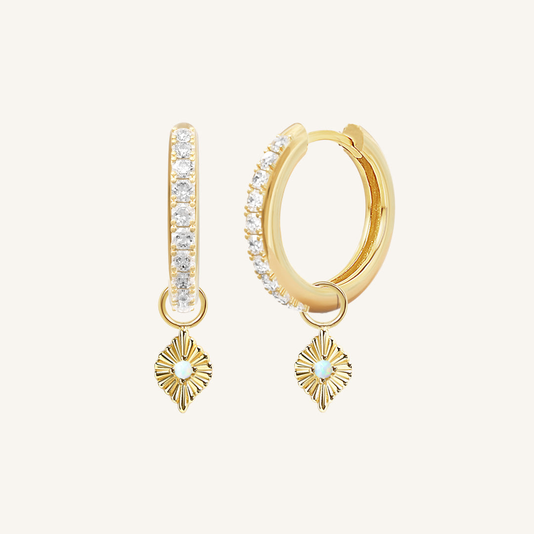 A pair of gold hoop earrings with cubic zirconia and diamond shaped hoop charms featuring a faux opal