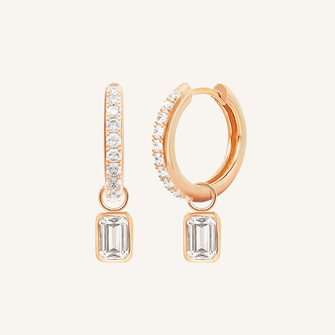 A pair of rose-tone radiant crystal hoop earrings with charm drops.