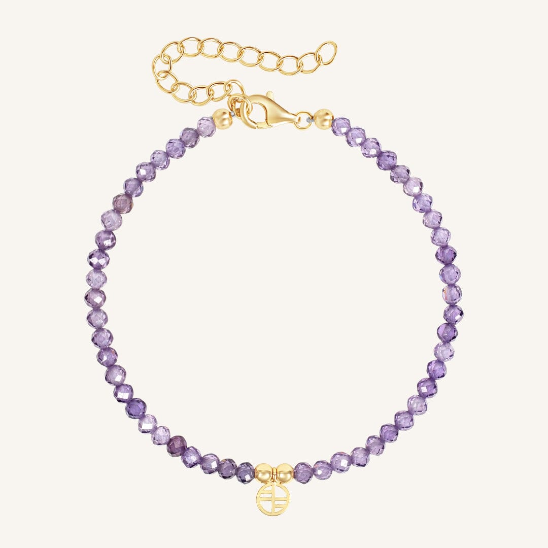 Purple beaded bracelet with gold clasp on a white background