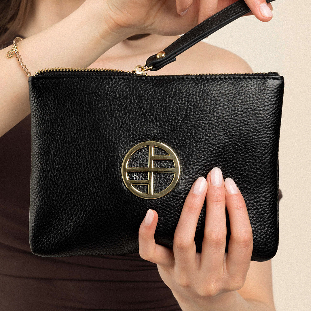 A black genuine leather pouch with a gold metal emblem and a wrist strap.