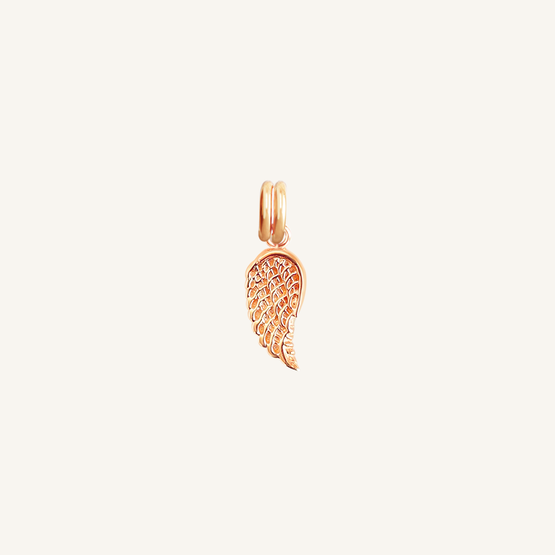 A rose-coloured angel wing charm with intricate details