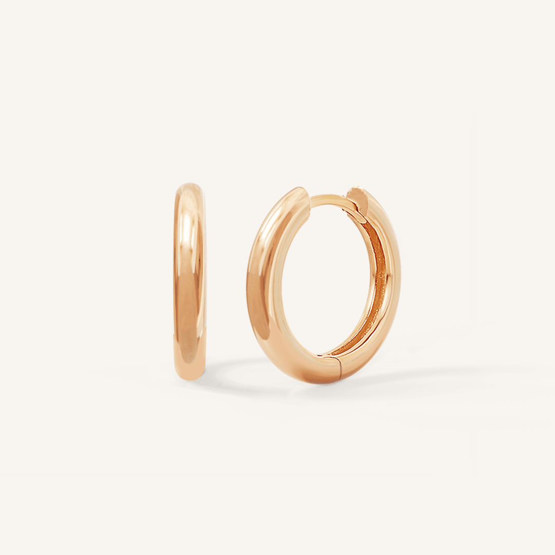 A pair of rose-colored hoop earrings on a white background