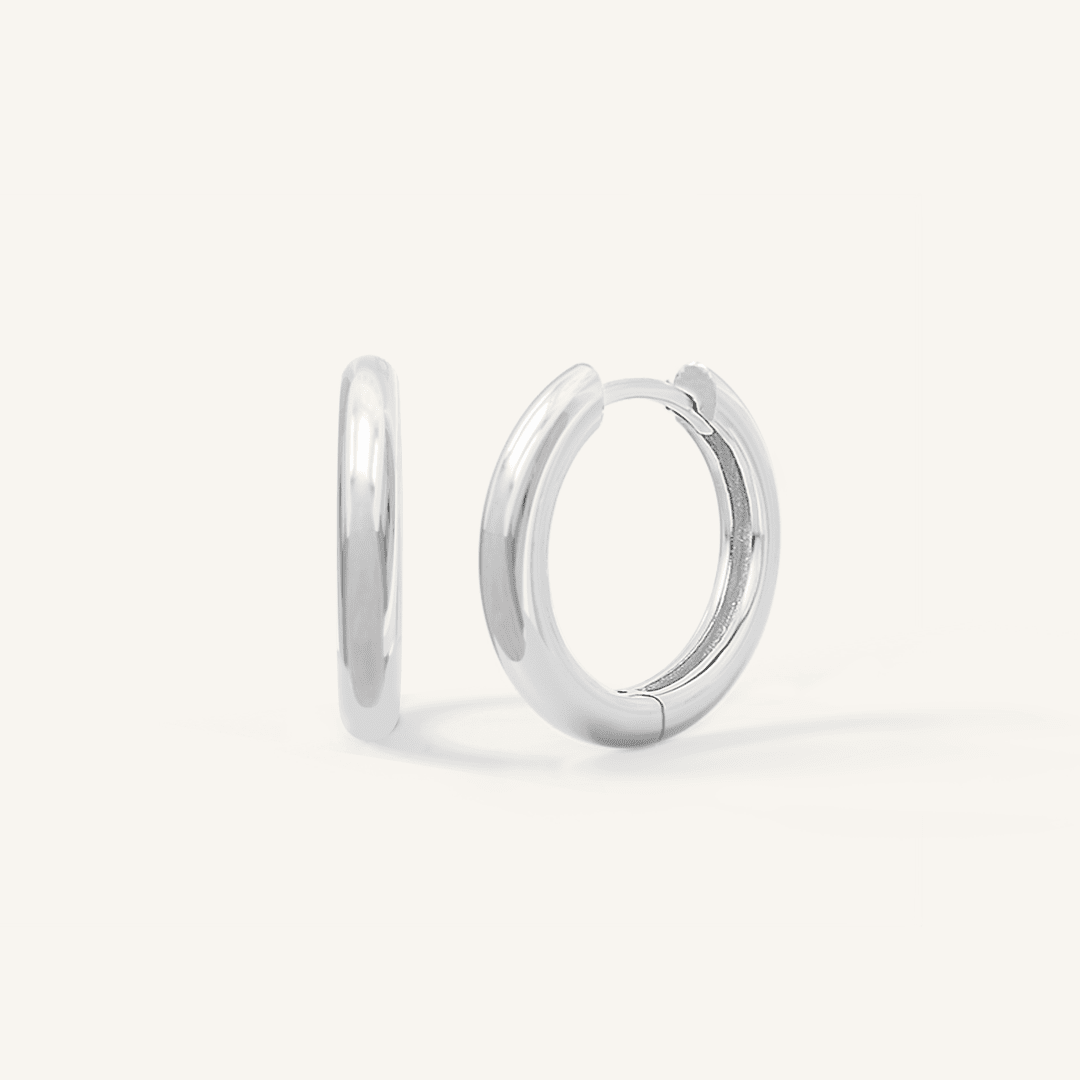 A pair of silver-colored hoop earrings on a white background