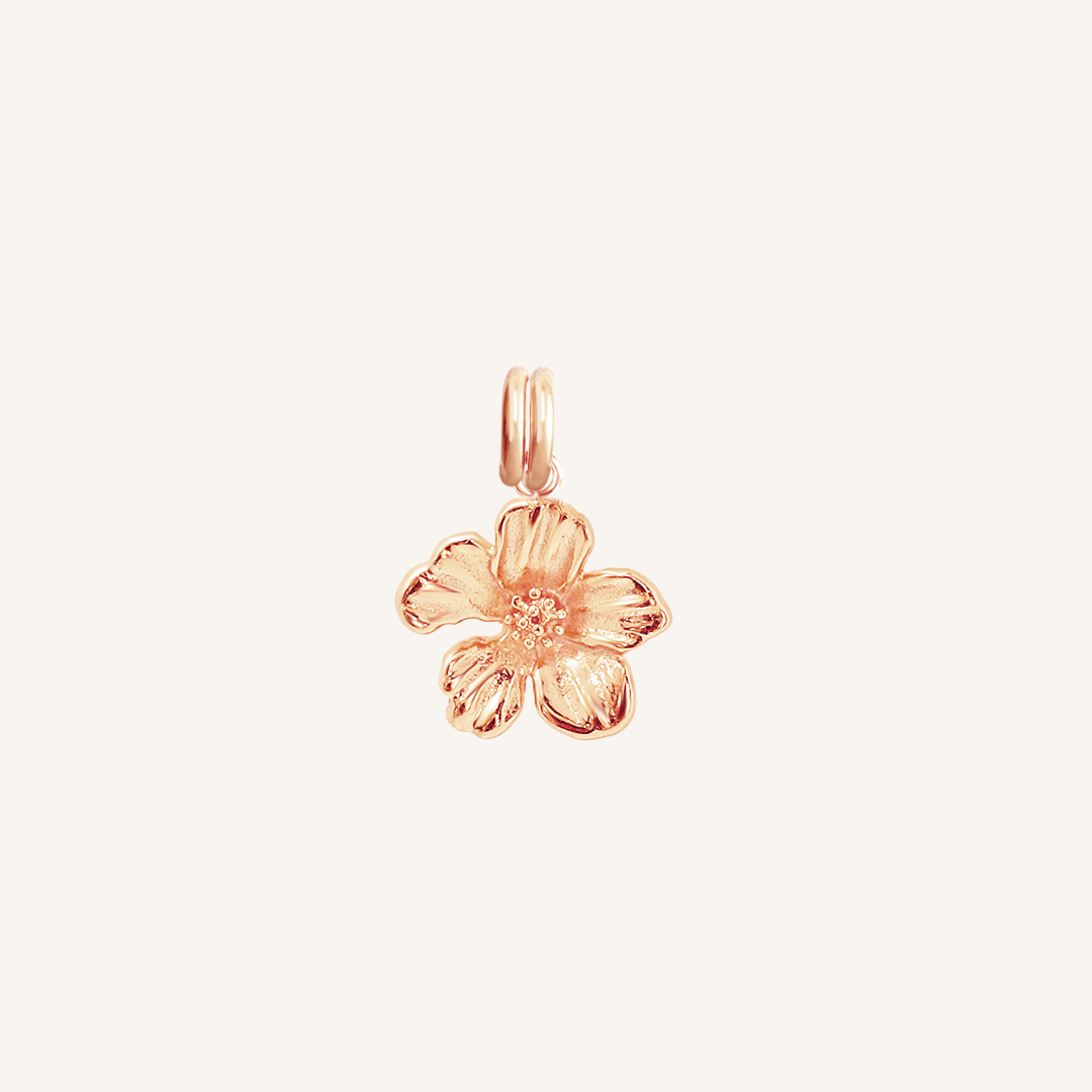 A rose-colored metal charm in the shape of an Azalea flower.
