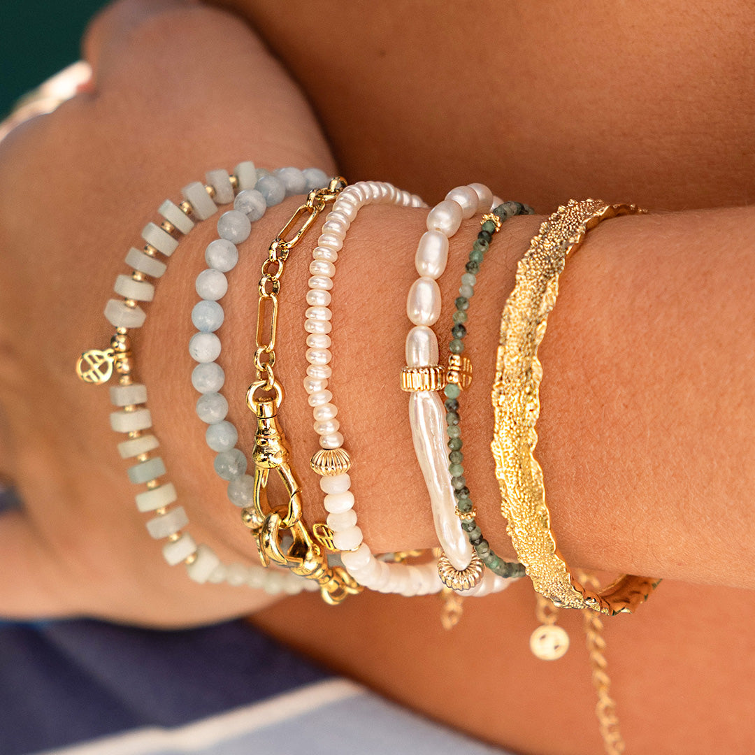 Close-up of a person's arm wearing multiple bracelets on a blurred background
