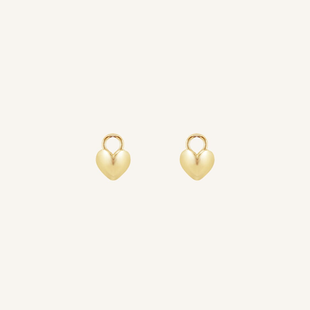 A pair of heart-shaped gold hoop charms against a white background