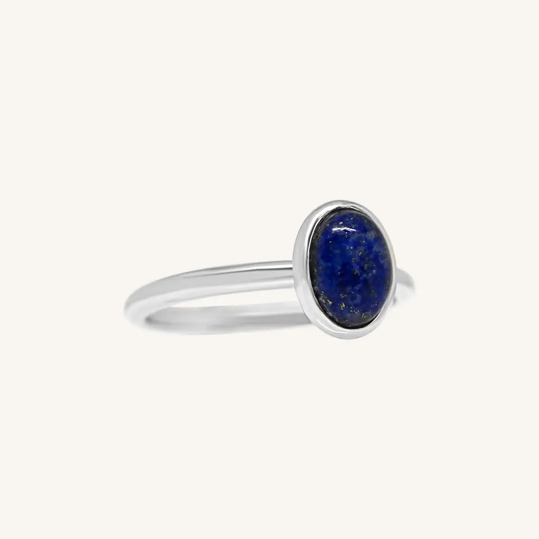 A silver ring with a deep-blue lapis stone set in a thinner band.