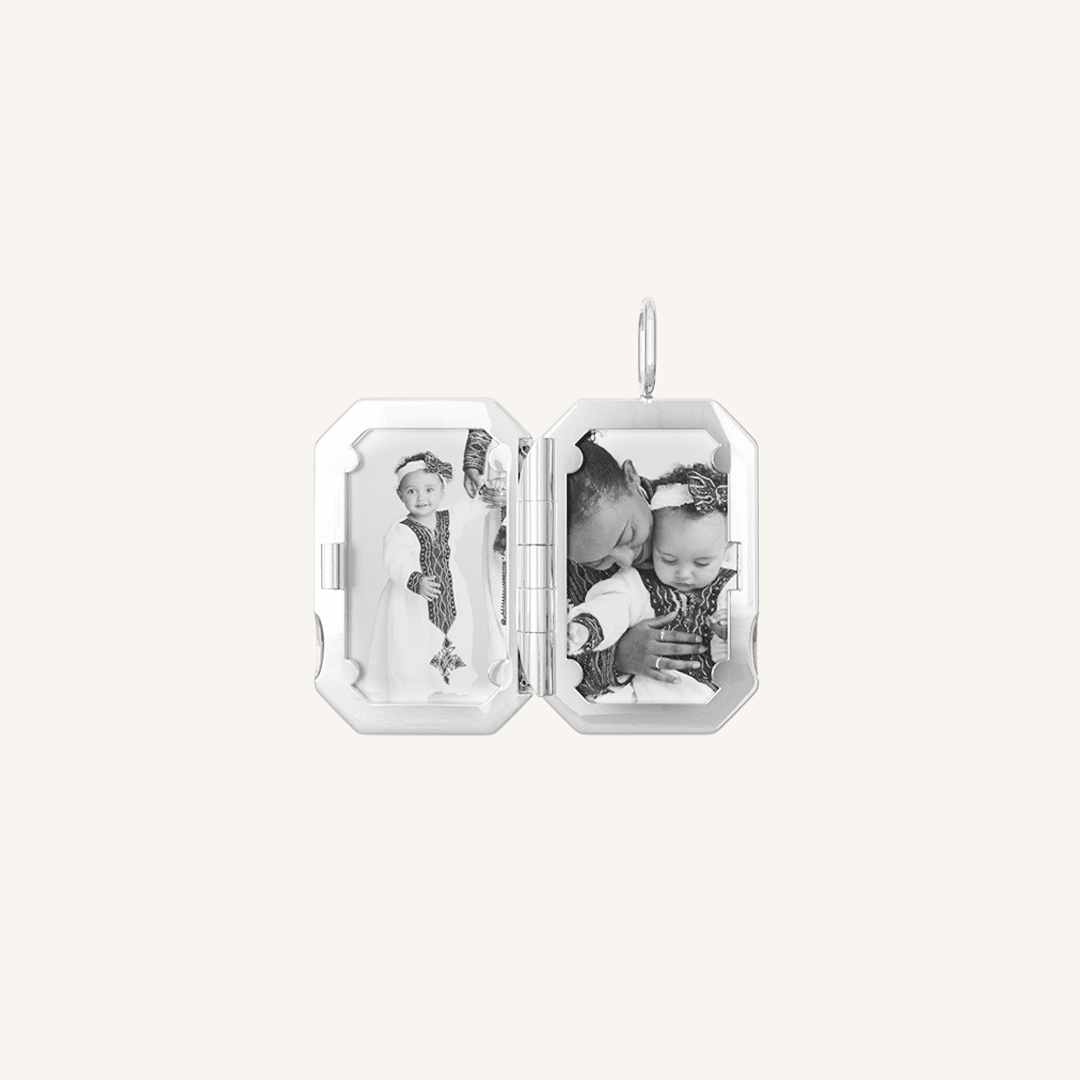 A silver bevel photo locket opened to display photographs inside.