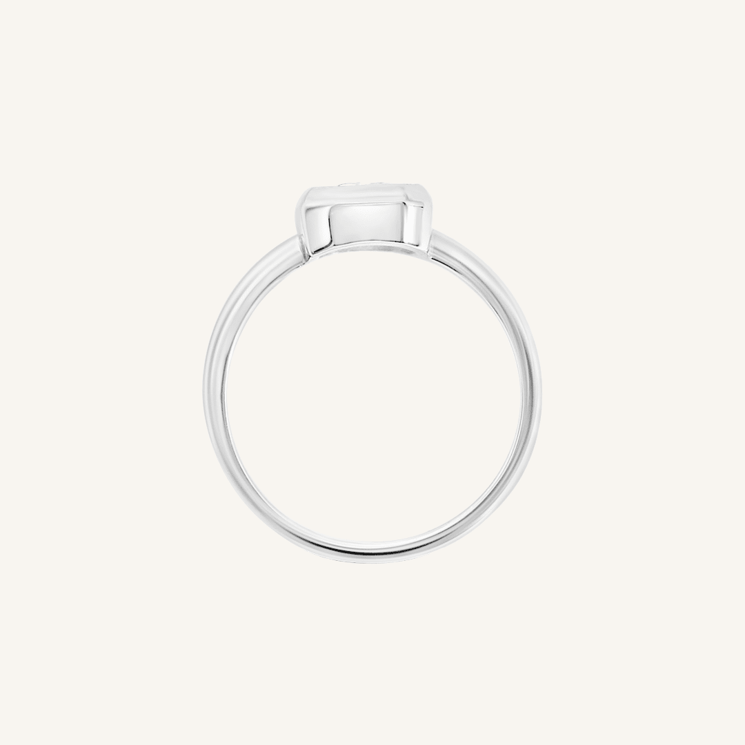 A silver-coloured ring with a white cubic zirconia, bezel set in a rectangular frame with a smooth, polished band, side profile
