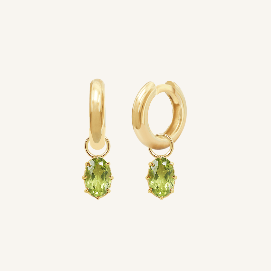 A pair of gold-tone hoop earrings with olive green charms attached to them.