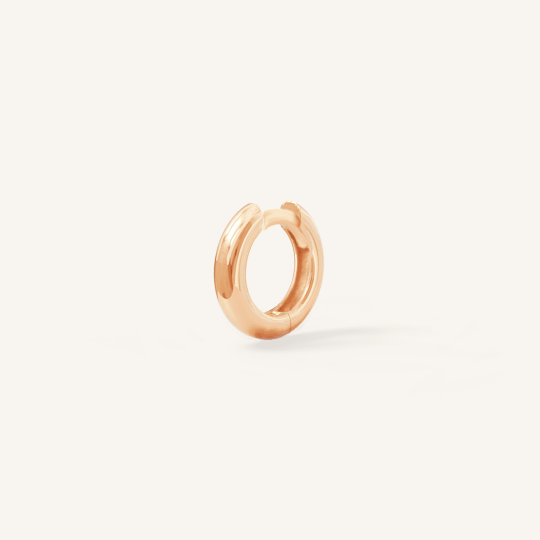 A rose huggie hoop earring on a white background.