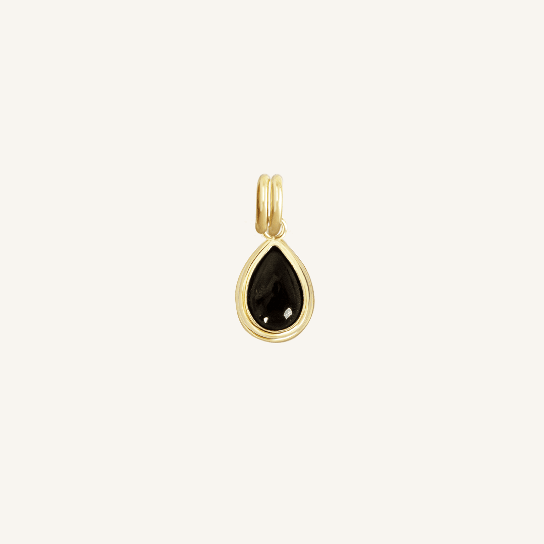 A gold charm with a teardrop-shaped black onyx stone.
