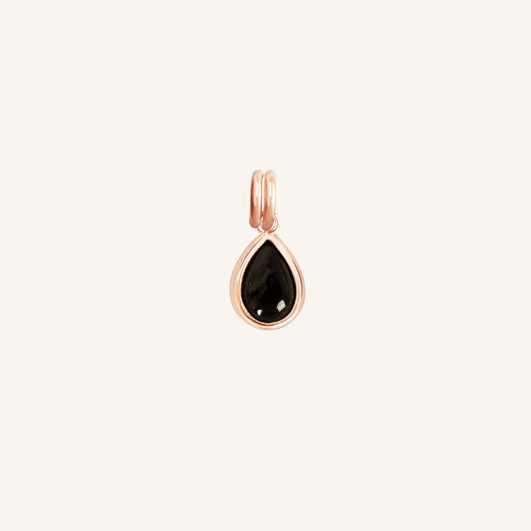 A rose gold charm with a teardrop-shaped black onyx stone.
