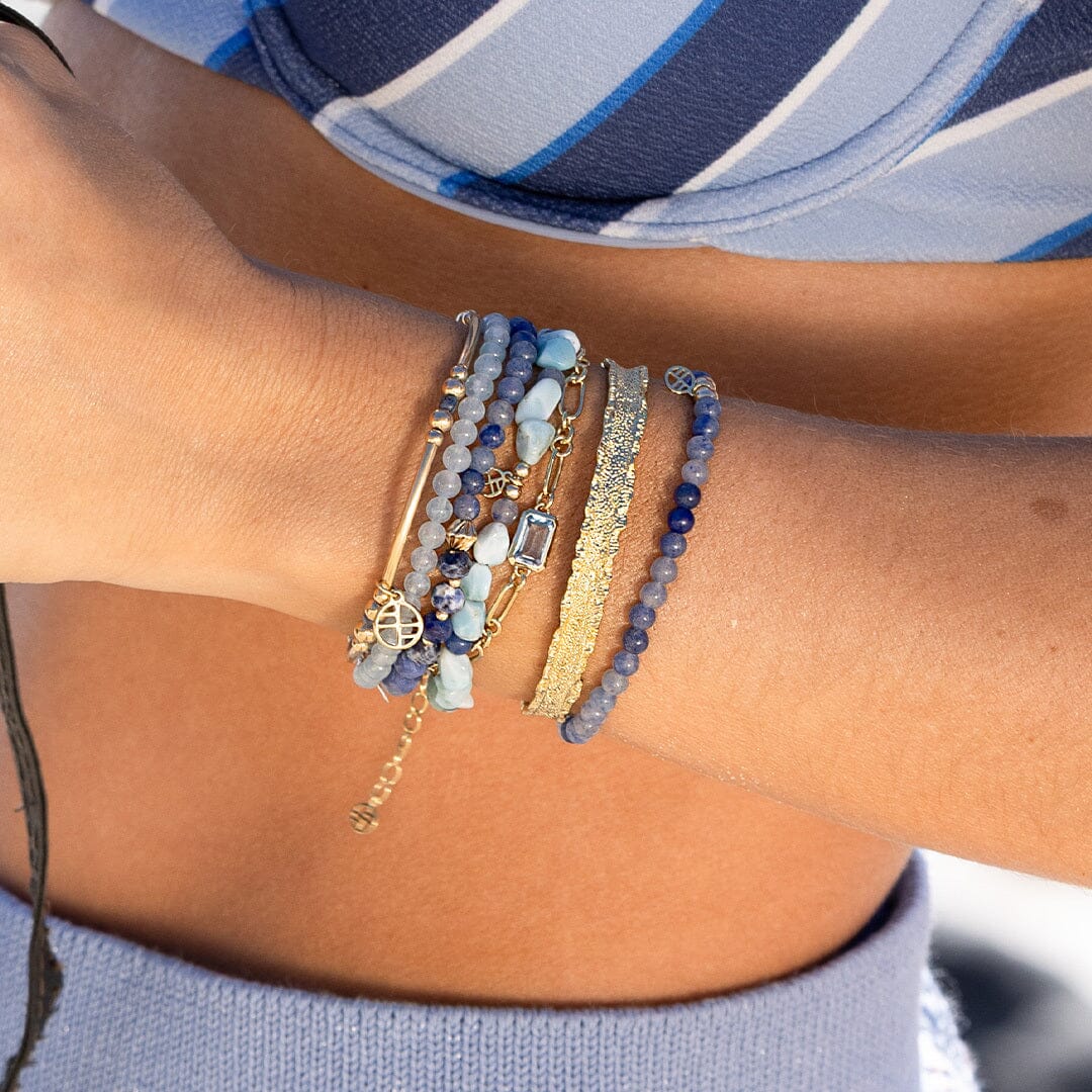 Close-up of a wrist wearing multiple bracelets with a blurred background