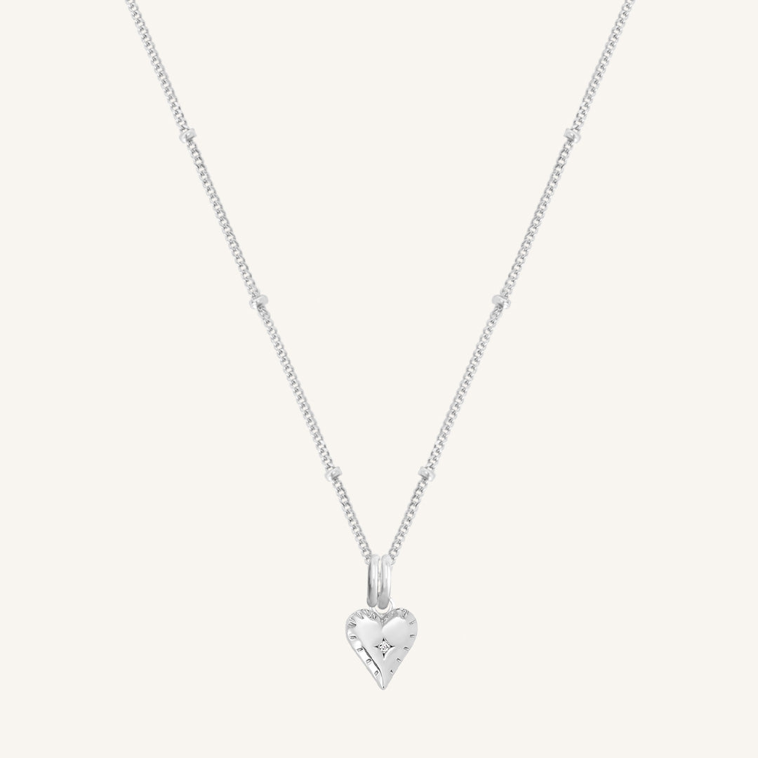 A silver-tone heart-shaped charm necklace with an adjustable chain.