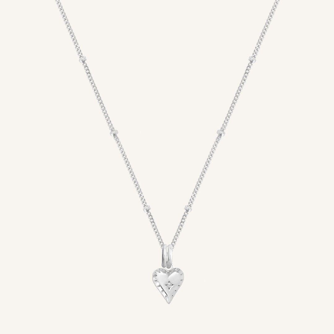 A silver-tone heart-shaped charm necklace with an adjustable chain.
