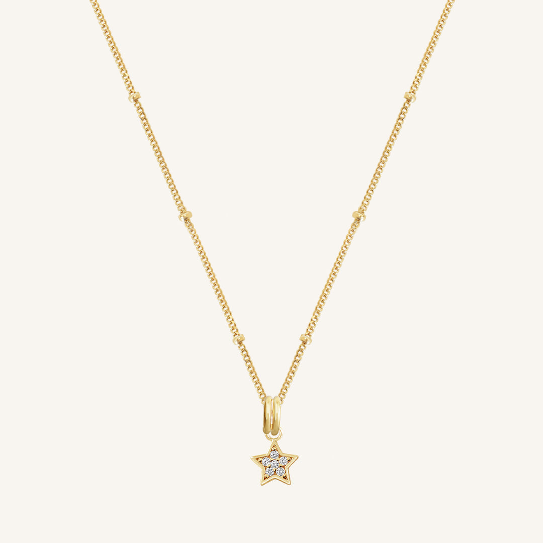 A gold necklace featuring a star-shaped charm pendant with cubic zirconias in the centre.