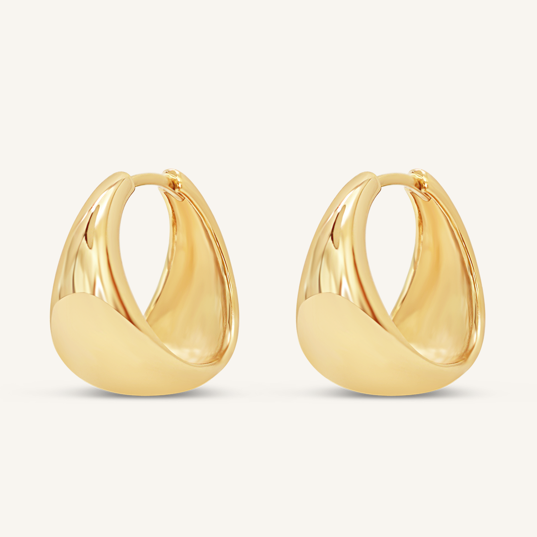A pair of gold-colored chunky hoop earrings on a white background.