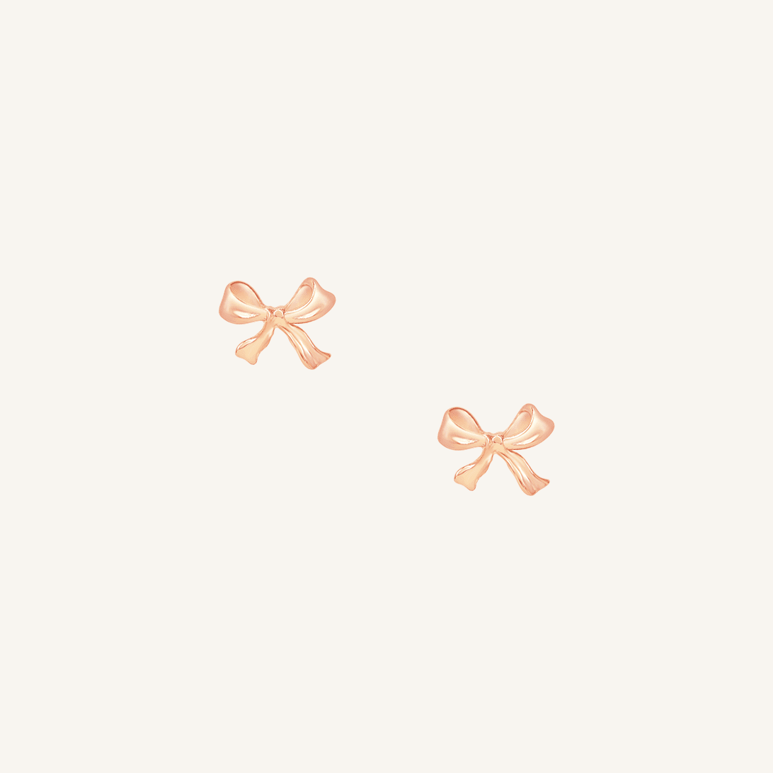 A pair of rose bow stud earrings on a white background