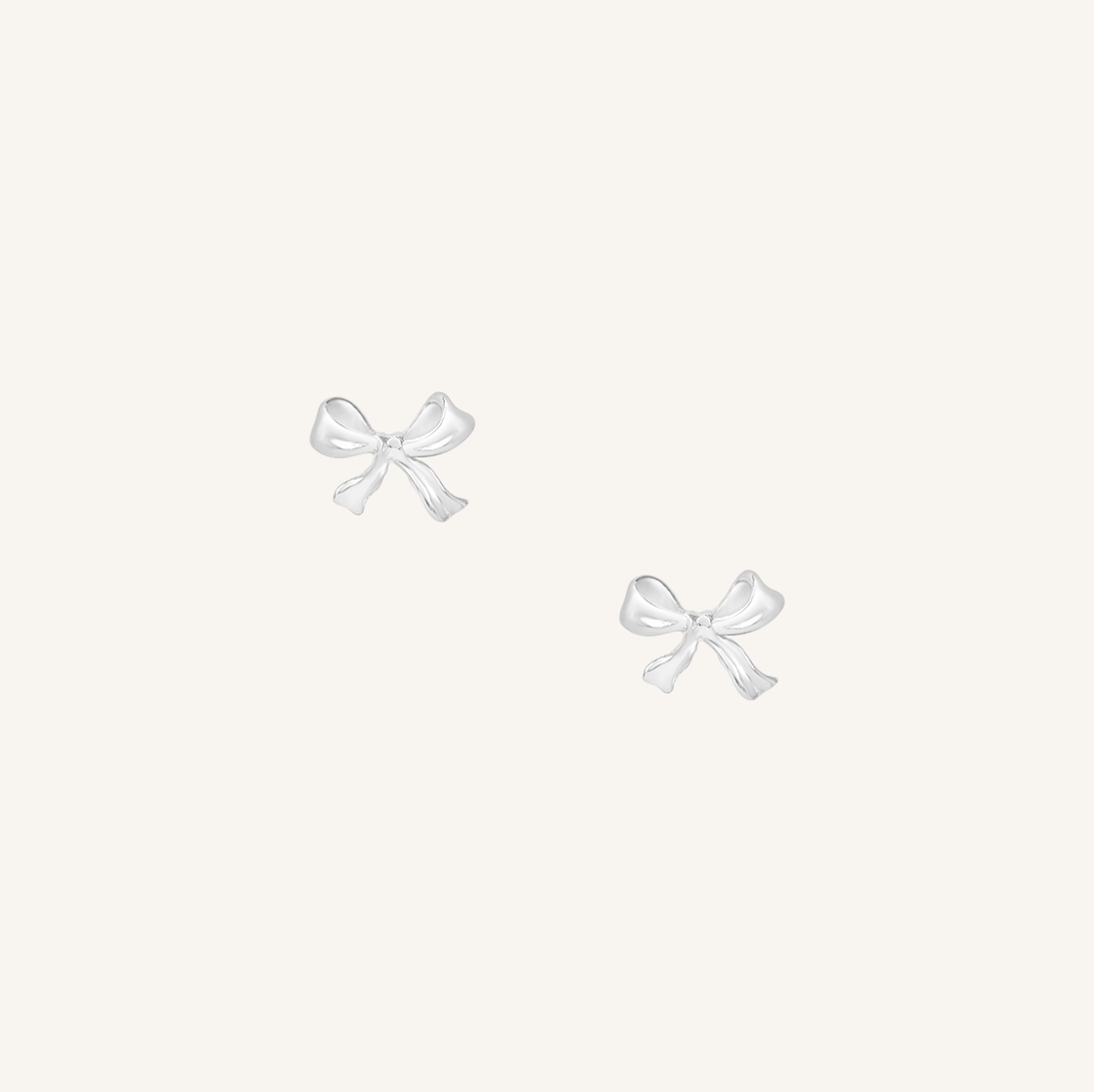 A pair of silver bow stud earrings on a white background