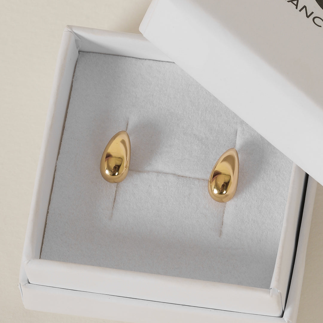 A pair of gold stud earrings with a smooth finish, displayed in white box.