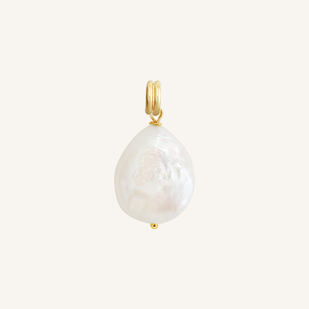 A medium sized pearl charm with gold findings, on white background