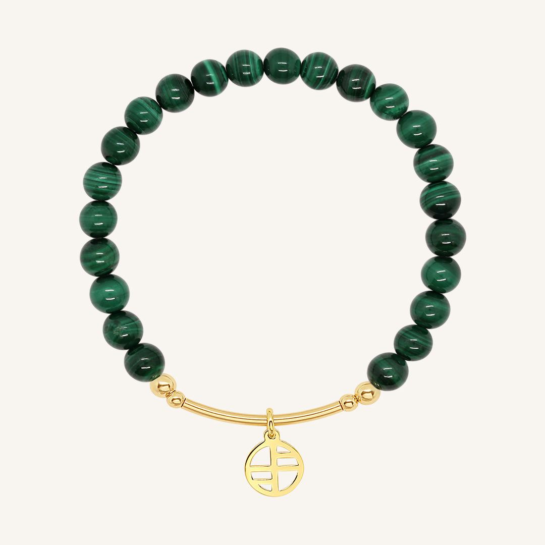 A beaded malachite charm bracelet with green stones and a gold-tone charm, displayed against a white background.