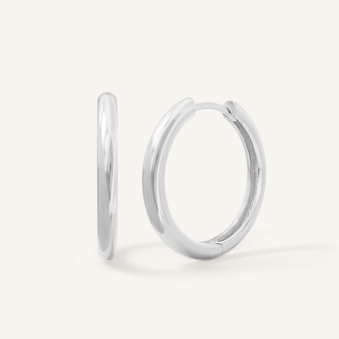 A pair of silver-tone hoop earrings on a white background