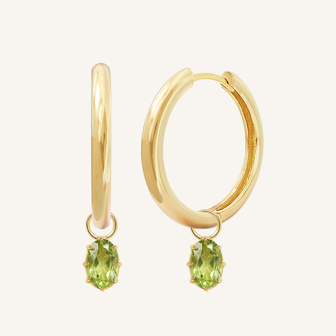 A pair of gold-tone hoop earrings with olive green charms attached to them.
