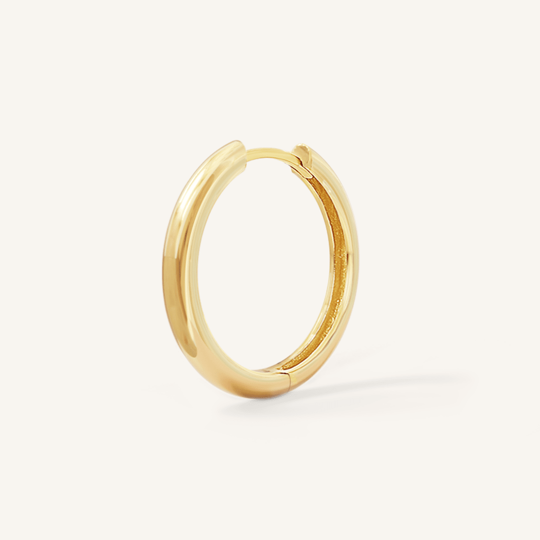 A gold hoop earring on a white background