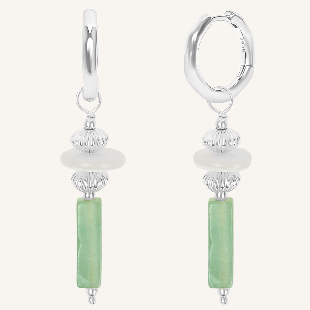 Silver hoop earrings with green cylindrical beads on a white background