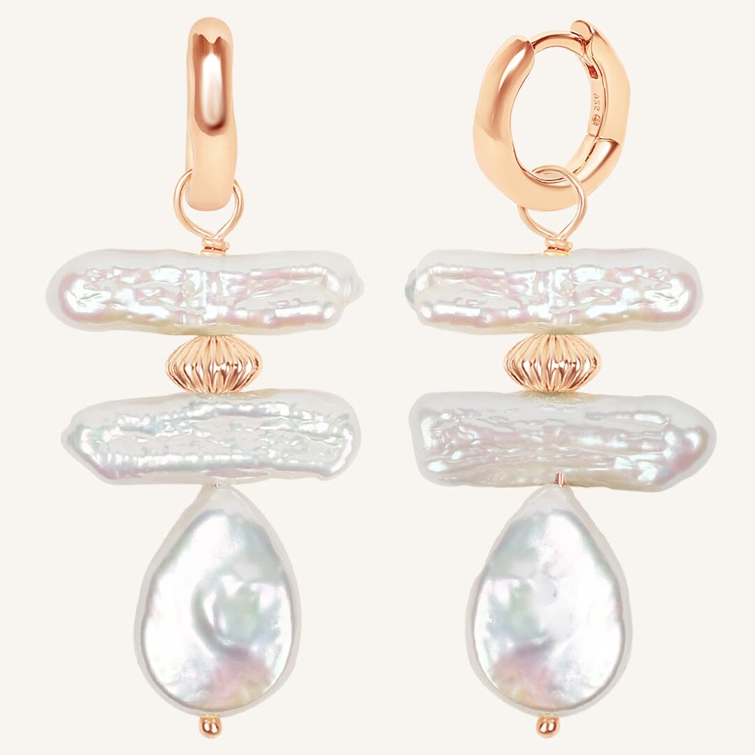 Pair of pearl earrings with rose gold accents on a white background