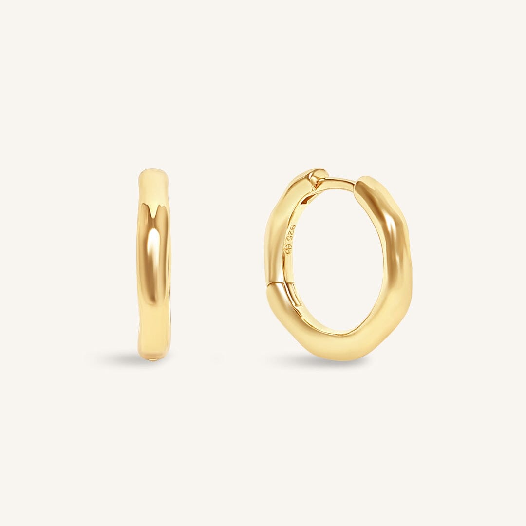 Gold hoop earrings on a light beige background