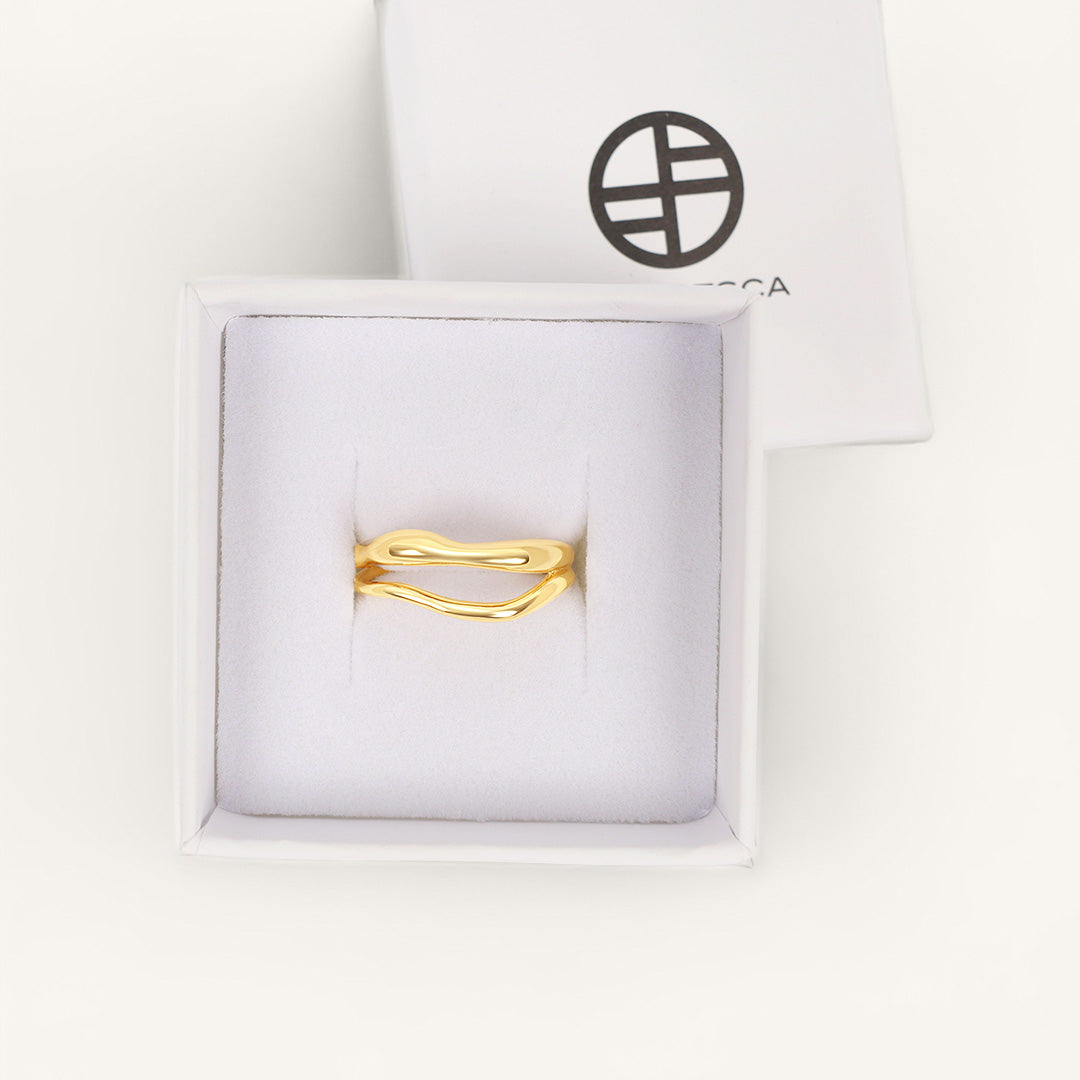 Gold ring in a white box with a brand logo on a white background