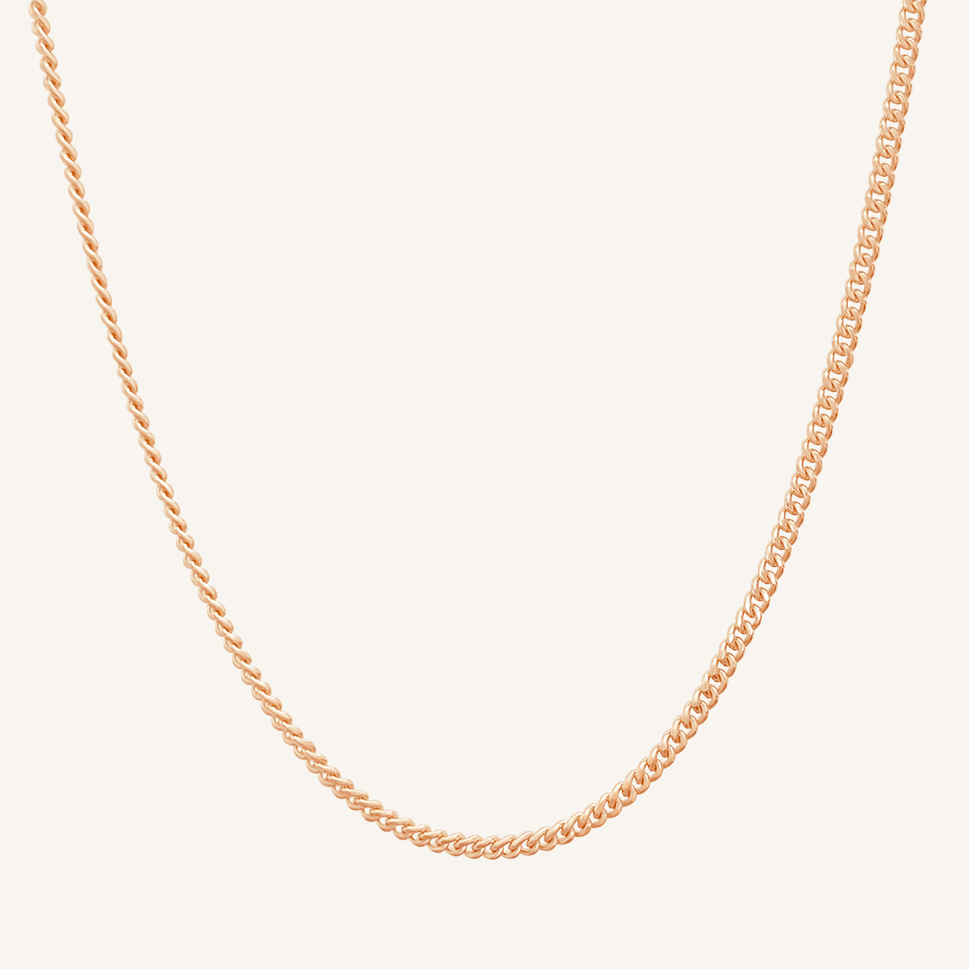 Rose gold chain necklace on a light beige background