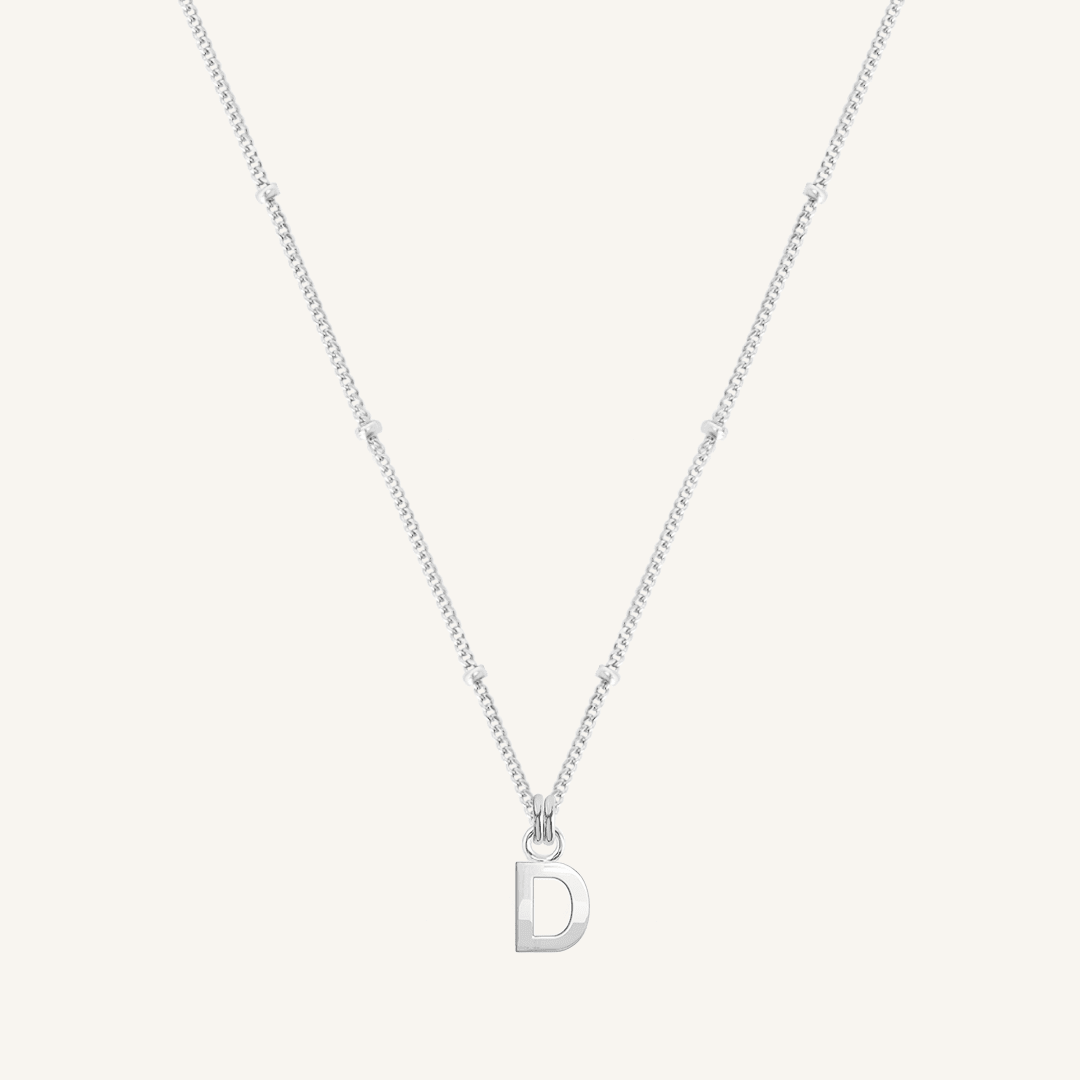 Silver necklace with a 'D' pendant on a light gray background