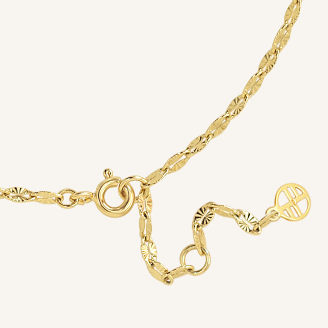 Gold necklace with various links on a white background