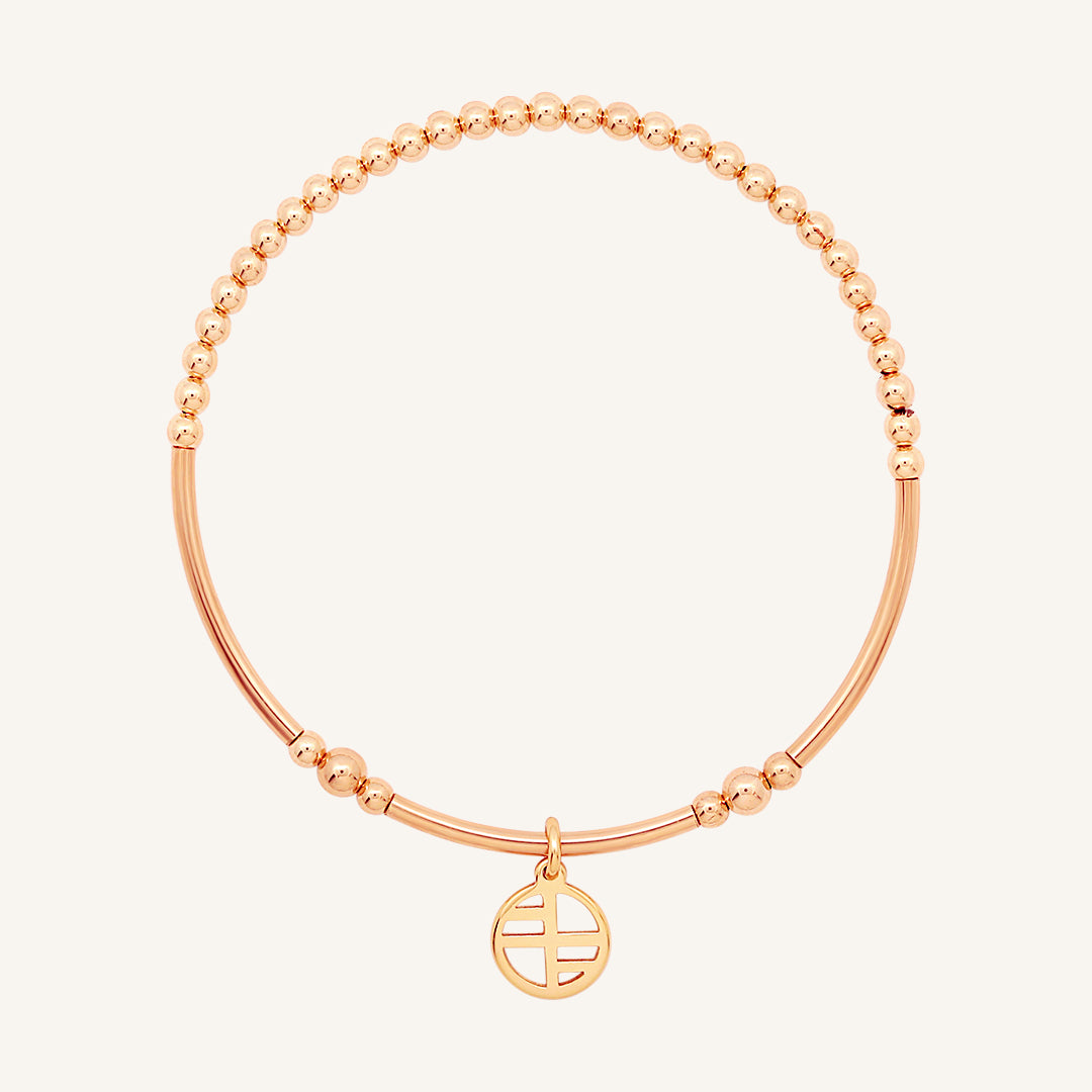 A rose-tone charm bracelet with a beaded design and a charm pendant in the center.