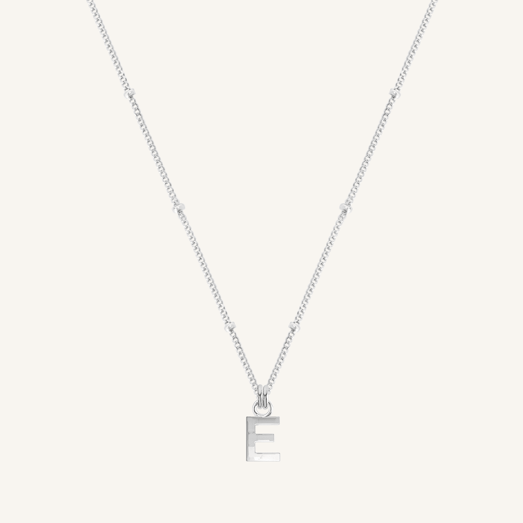 Silver necklace with a letter 'E' pendant on a light gray background