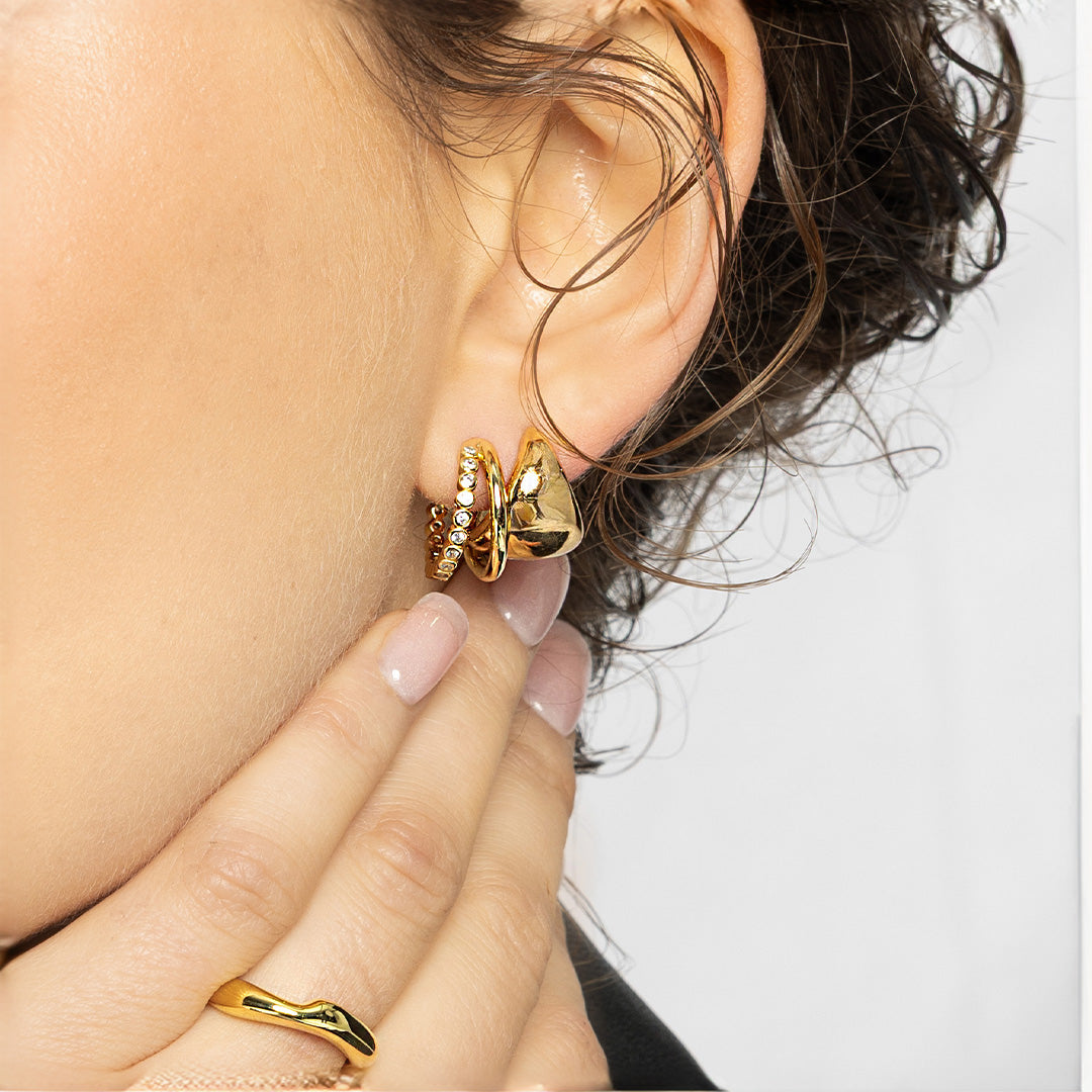 Gold hoop earrings being worn with a blurred background